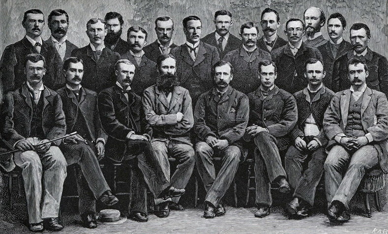 Black-and-white group portrait of the two dozen members of the Lady Franklin Bay Expedition in civilian dress, seated and standing in two rows, before their 1881 departure.